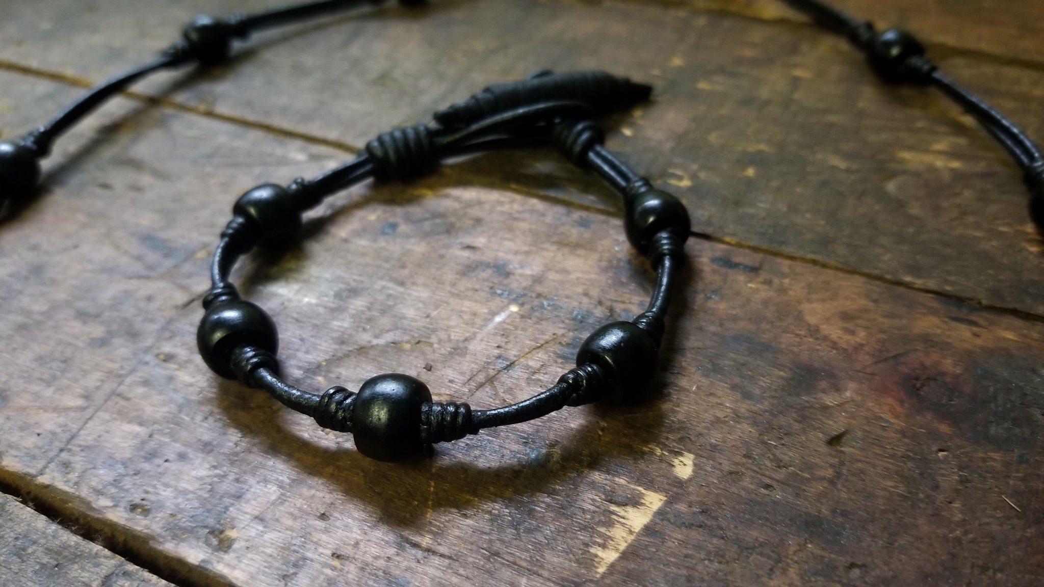 Chuma knot bracelet; black leather cord with black onyx African Trade Beads, Bison Leather Button and Loop Clasp