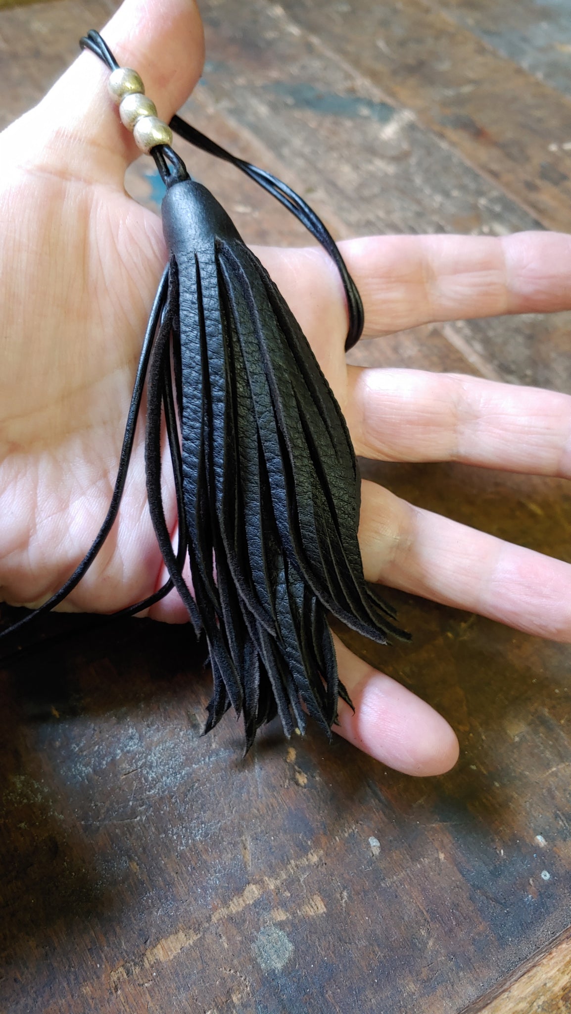 deerskin leather tassel pendant with silver African metal beads in hand